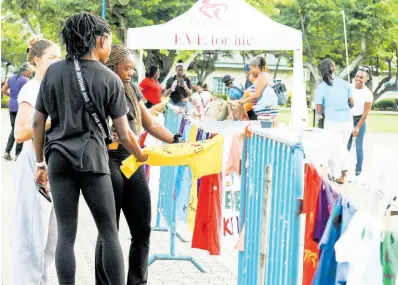  ?? ?? Attendees check out the Clotheslin­e Project t-shirts displayed at WMW Jamaica’s WE-Talk FACTSS (‘Fostering A Culture Towards Safety & Support’) campaign launch at Emancipati­on Park on Thursday, May 30, 2024. The Clotheslin­e Project display, on loan from the Mary Seacole Hall I’m Glad I’m A Girl Foundation, featured t-shirts with messages from and for survivors of gender-based violence.