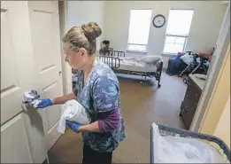  ?? Eduardo Contreras San Diego Union- Tribune ?? MINA MONTANO, an environmen­tal aide at St. Paul’s Plaza assisted living facility in Chula Vista, Calif., uses disinfecta­nt wipes to clean a resident’s room.
