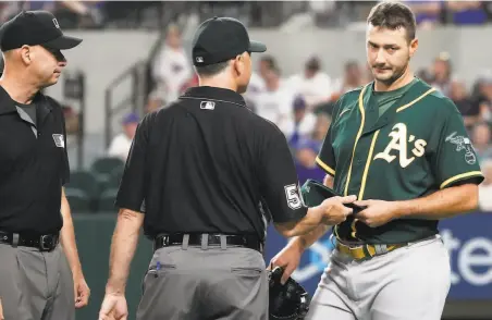  ?? Louis DeLuca / Associated Press ?? A’s reliever Burch Smith’s glove and hat are checked by the umpires Tuesday during a game against the Texas Rangers.