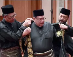  ??  ?? Mukhriz (right) helps Datuk Ahmad Kassim (centre) to put on his formal Speaker coat. — Bernama photo