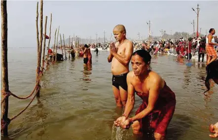  ?? — EPA ?? Solemn ritual: Devotees bathing and offering prayers at the banks of Sangam in Allahabad.