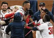  ?? AP ?? Atlanta Braves’ Eddie Rosario is congratula­ted by teammates after hitting the game winning RBI single during the ninth inning against the Los Angeles Dodgers in Game 2 Sunday. The Braves defeated the Dodgers 5-4.