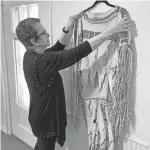  ??  ?? Yvonne Kauger works on a display of a Cheyenne buckskin dress made by Margaret Riggs Curtis and Jeanette Riggs Howlingcra­ne.