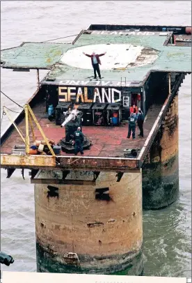  ??  ?? AN ENGLISHMAN’S HOME:
Owner Roy Bates, with his arms aloft, on the Sealand landing platform