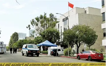  ??  ?? Staff from the Coroners office remove the body from the front of the Chinese consulate (right) after a man of Chinese descent fired several shots at the building then committed suicide near it’s entrance, in Los Angeles, California. — AFP photo