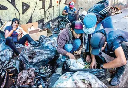  ?? MERIDITH KOHUT/THE NEW YORK TIMES ?? Families salvage food scraps from garbage bags in downtown Caracas, Venezuela, on Febuary 10.