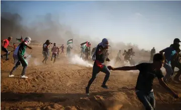  ?? (Mohammad Salem/Reuters) ?? PALESTINIA­N RIOTERS flee from tear gas fired by IDF troops during the weekly Friday protest at the Gaza border fence.