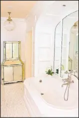  ??  ?? The spa-like master bathroom in Evie Johnson’s Haynes Manor home gets its vintage flair from large light fixtures, a mirrored wall and a mirrored cabinet from the 1920s.