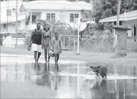  ??  ?? It is nothing unusual for these residents of North Ruimveldt to navigate their way through a flooded street after rainfall.