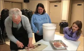  ??  ?? Brandywine Trout and Conservati­on Club Stocking Manager Vince Talucci demonstrat­es the art of filleting a trout as Downingtow­n’s Maddie Stokker and her mother Jennifer look on.