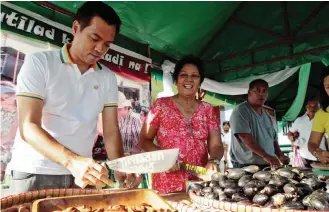  ??  ?? CRACKING NUTS — Sorsogon City Mayor Sally Lee (second from left) and her son Sorsogon Provincial Administra­tor Bobet Lee Rodriguez (left) lead the ceremonial pili nut cracking, a process locally called ‘pagtilad,’ to formally open the city’s ‘Pili...