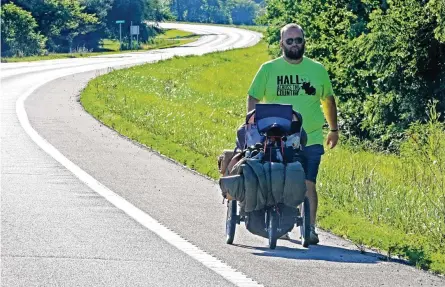  ?? BILL LACKEY/STAFF ?? Joe Hall walks along U.S. 40 between South Vienna and Springfiel­d on Thursday. Hall is walking across America as a Childrens Hospital/ mental health fundraiser.