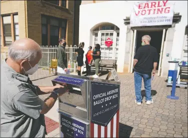  ?? (File Photo/AP/John Bazemore) ?? A voter submits a ballot in October in an official drop box during early voting in Athens, Ga. On Friday, The Associated Press reported on stories circulatin­g online incorrectl­y asserting “Georgia’s new anti-voting law makes it a jail-time crime to drop off grandma’s absentee ballot in a drop box.”