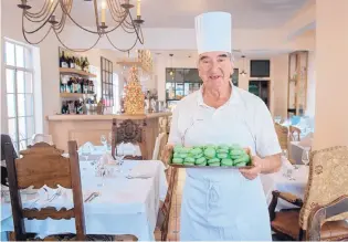  ?? EDDIE MOORE/ JOURNAL ?? Chef Paul Perrier poses with a tray of macarons at Chez Mamou. A master pastry chef with a diploma from La Chaine des Rotisseurs, he has been using the same macaron recipe for 60 years.