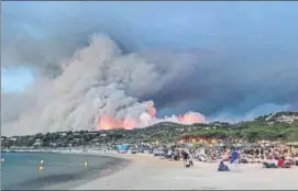  ?? AFP ?? Evacuated people take refuge on the beach and look at a fire burning the forest in BormeslesM­imosas, France on Wednesday.