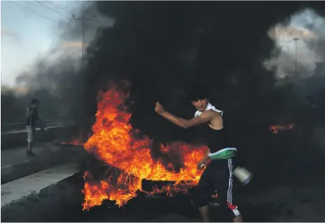  ?? AP ?? A protester throws stones while others burn tyres during a protest at the Erez border crossing between Gaza and Israel on Tuesday