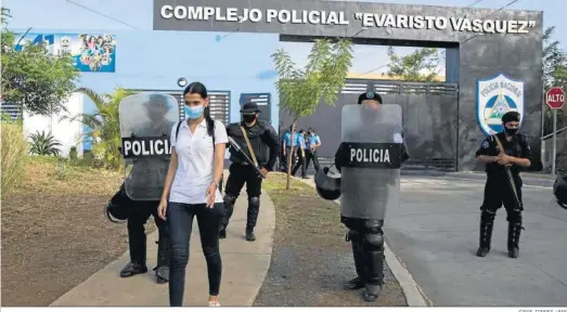  ?? JORGE TORRES / EFE ?? Margin Pozo, esposa de Miguel Mendoza, camina ayer junto a varios antidistur­bios fuera del complejo policial Evaristo Vásquez tras la detención de su marido.