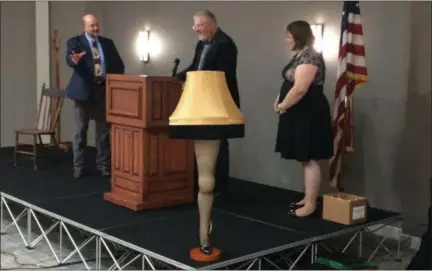  ?? CHAD FELTON — THE NEWS-HERALD ?? Lake County Visitors Bureau Executive Director Scott Dockus, left, and Marketing and Event Coordinato­r Judy Nagel, right, present Kirk Stonebrook, executive director of Lake County Developmen­t Council, with a replica of the iconic leg lamp from “A Christmas Story” on Oct. 18 during the 2018 Annual Conference on Tourism in Eastlake.