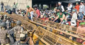  ??  ?? Members of the Bhartiya Kisan Union jump off the barricades as they protest at the Delhi-Gaziabad border on Sunday. — ANI