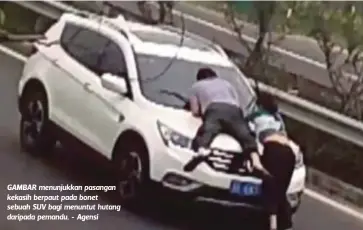  ??  ?? GAMBAR menunjukka­n pasangan kekasih berpaut pada bonet sebuah SUV bagi menuntut hutang daripada pemandu. - Agensi