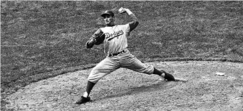  ?? HARRY HALL / ASSOCIATED PRESS ?? Sandy Koufax pitches against the Chicago Cubs for the Brooklyn Dodgers in 1957. He would become the best lefthander of all-time in the minds of many and now, along with fellow Hall of Famer Jackie Robinson, has a bronze statue at Dodger Stadium, unveiled in 2022. Nicknamed “The Left Arm of God,” he was a strikeout machine and won three Cy Young Awards. He pitched four no-hitters and a perfect game.