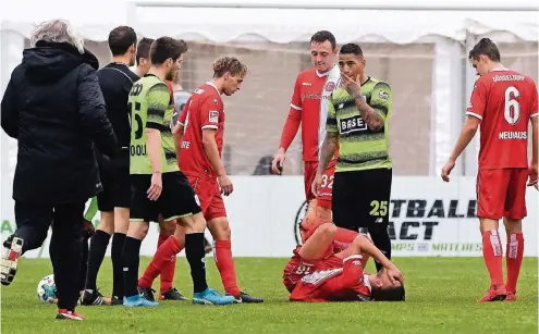  ?? FOTO: WOLFF ?? Gökhan Gül liegt am Boden, während Teamarzt Ulf Blecker (li.) herbeieilt. Florian Neuhaus, Robin Bormuth und Julian Schauerte (in Rot v.re.) sehen zu.