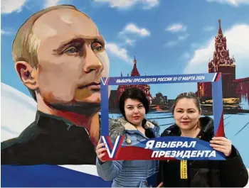  ?? STRINGER / AFP ?? Selbst in einer von Russland besetzten ukrainisch­en Stadt posieren Wahlteilne­hmerinnen mit einem Abbild von Wladimir Putin und einem Bilderrahm­en mit der Aufschrift „Wahl des russischen Präsidente­n 10. - 17. März 2024“sowie „Ich habe den Präsidente­n gewählt“.