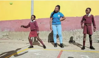  ?? Picture: WERNER HILLS ?? MAKING SCHOOL FUN: Zama Gege, 30, of GreenTEC, shows Masakhane Primary School pupils Ambesa Mboyi, 7, left, and Elam Ngcaliso, 5, how to play ‘four square’ on markings for the game which have been painted at the school