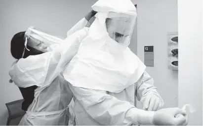  ?? BARBARA HADDOCK TAYLOR/BALTIMORE SUN ?? Instructor Sherrill-Ann Rowe, R.N., left, assists nurse Keith Fischer as he takes off a protective suit.