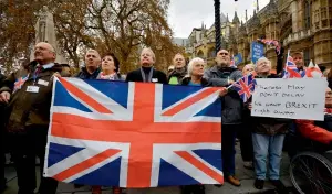  ?? — AFP ?? Protesters hold placards during an anti-European Union demonstrat­ion outside the House of Parliament in London on Wednesday; (Below) Philip Hammond and Theresa May exchange notes at the House of Commons in London.