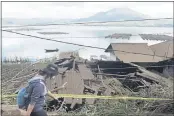  ?? DEWA RAKA — THE ASSOCIATED PRESS ?? A woman walks past houses by Lake Batur that were damaged by an earthquake-triggered landslide in Bangli, on the island of Bali, Indonesia, on Saturday.