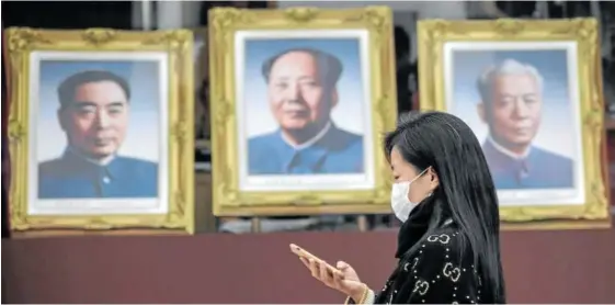  ?? Foto: Efe ?? Una mujer pasa frente a los retratos de los exlíderes Mao Zedong, en el centro, Chu Enlai y Liu Shaoqi.