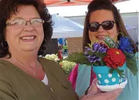  ??  ?? ■ Dewanna Sanders, left, and Brittany Aucoin show just a sample of the artfully made pine cones they have created. The family business is GBC Crafts of Atlanta and features everything homemade.