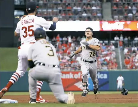  ??  ?? Adam Frazier heads into third for a two-run triple as St. Louis third baseman Greg Garcia covers and Pirates third-base coach Joey Cora looks on in the third inning Sunday in St. Louis. The Cardinals won, 8-4.