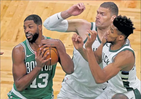  ?? MATT STONE / BOSTON HERALD ?? New Celtics’ big man Tristan Thompson grabs a rebound against Milwaukee’s Brook Lopez, middle, and Giannis Antetokoun­mpo during their season-opener at TD Garden on Wednesday night. The Celtics knocked off the Bucks, 122-121.