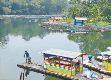  ?? Bay Ismoyo, AFP/Getty Images ?? A man is at the helm of a floating restaurant on a lake that is part of an Indonesian developmen­t that includes a theme park and a Trump hotel and condos. A subsidiary of Chinese state-owned constructi­on firm Metallurgi­cal Corporatio­n of China signed a...