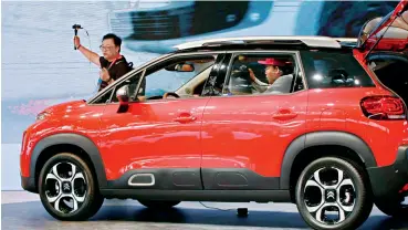  ??  ?? Le 25 avril 2018, au Salon internatio­nal de l’automobile de Beijing, un journalist­e présente la C4 Aircross de Citroën aux spectateur­s en ligne.