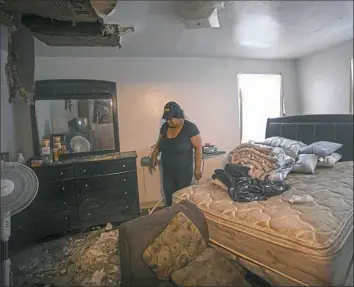  ?? Steve Mellon/Post-Gazette ?? Tawanda Miller looks at the debris from a collapsed ceiling Monday in the bedroom of her apartment at a complex in Penn Hills. Residents of the complex on Robinson Boulevard have until Thursday to move out of their apartments, which Penn Hills officials said are unsafe.