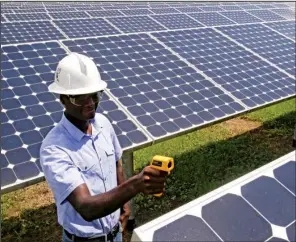  ?? AP/ JOHN RAOUX ?? Henry Plange, a power generation engineer, checks temperatur­es of solar panels at the Space Coast Next Generation Solar Center in Merritt Island, Fla., earlier this month.