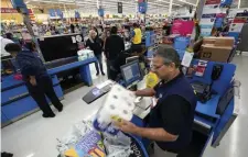  ?? AP FILE ?? RETAIL RAISE: A Walmart associate works at checkout in a Houston store. Walmart is increasing starting pay at 500 of its 4,700 U.S. stores to $12 an hour.