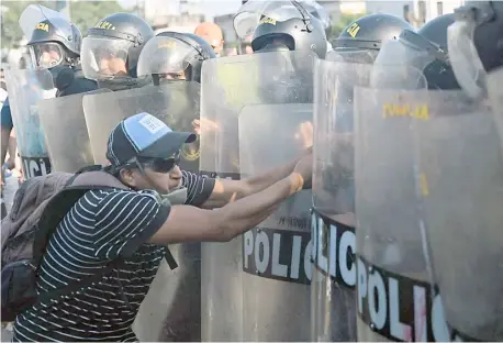  ?? ERNESTO BENAVIDES/AGENCE FRANCE-PRESSE ?? ACTIVIST confronts riot police during a protest demanding the resignatio­n of Peru’s President Dina Boluarte in Lima,. Civil unrest since the ouster of Boluarte’s predecesso­r, Pedro Castillo, in early December has left 46 people dead and prompted the government to impose a state of emergency in violence-hit areas.