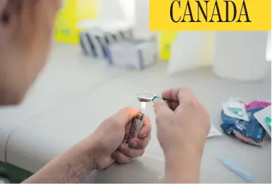  ?? NICK KOZAK FOR POSTMEDIA NEWS ?? A drug user prepares heroin for injection at a pop-up safe injection site in Moss Park in Toronto.