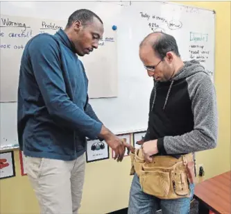  ?? BARRY GRAY THE HAMILTON SPECTATOR ?? WorkLINC is running training to prepare newcomers for LRT constructi­on. Justin Butoto, left, helps Sami Alakal fasten a toolbelt.