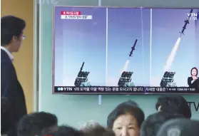  ?? AP FOTO ?? NEW MISSILE. A man watches a TV news program showing photos published in North Korea's Rodong Sinmun newspaper of North Korea's new type of cruise missile launch.