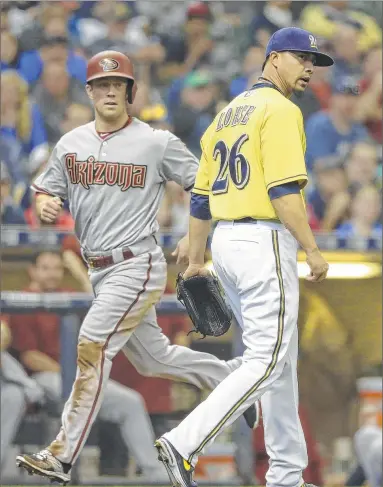  ??  ?? ASSOCIATED PRESS
The Diamondbac­ks’ Aaron Hill scores after Brewers pitcher Kyle Lohse made a throwing error on a bunt by Chris Owings.
