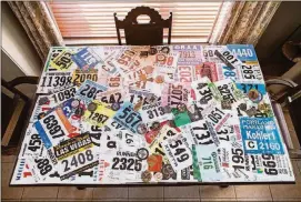  ?? TOM MCCARTHY JR. FOR AMERICAN-STATESMAN ?? Kent Kohler’s antique table serves as a display case for all of his race bibs and medals.