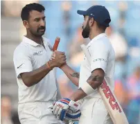  ?? AFP ?? Indian captain Kohli greets teammate Pujara at the end of the second day’s play of the second Test against Sri Lanka. —