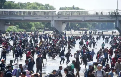  ?? GETTY IMAGES ?? CROSSING PATTERN: Migrants, mostly from Honduras, cross the Suichate River on the MexicoGuat­emala border Monday after being told they would not be allowed to cross the bridge, background. Above left, Mexican national guards try to block the migrants’ path.