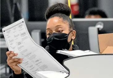  ?? AP ?? An election worker scans ballots in Georgia, where a second recount is under way at Donald Trump’s request as the US president’s legal team continues to mount seemingly futile challenges to the results in battlegrou­nd states.