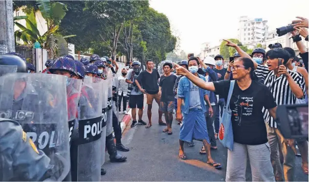  ?? Agence France-presse ?? ↑
Residents shout as police stand guard at the entrance gate of a Buddhist monastery where pro-military supporters took shelter after clashes in Yangon on Thursday.